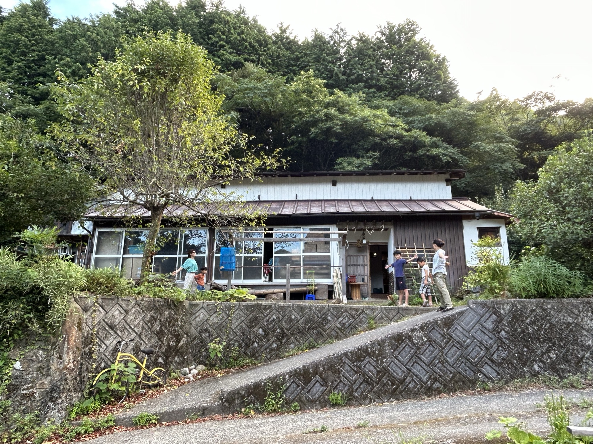 山に囲まれた家の前で過ごす家族