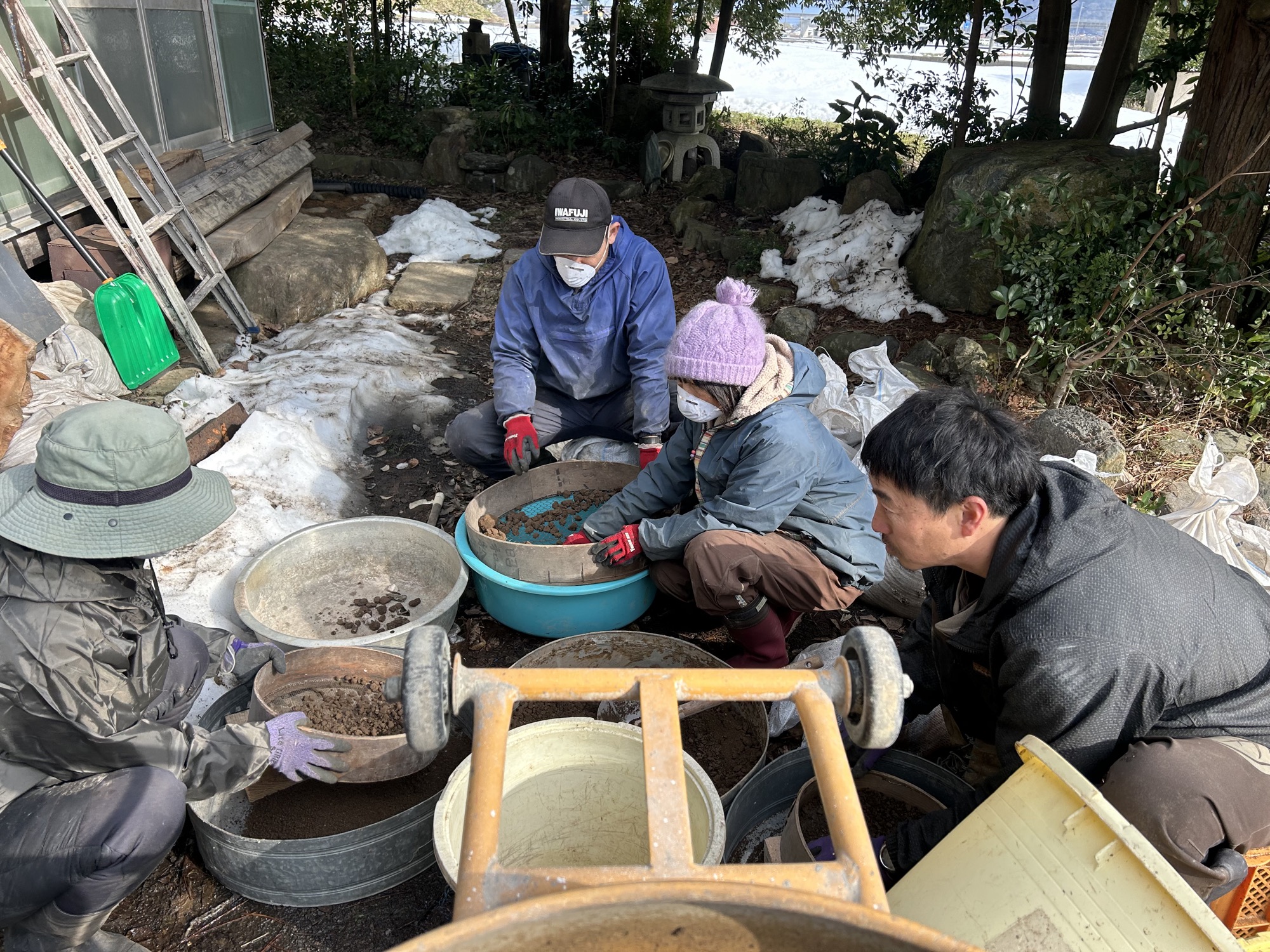 この家から出た土をふるって準備する様子